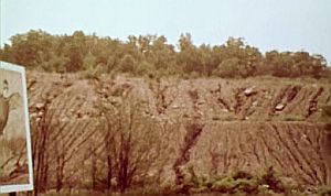 Eroded spoil piles & mined hillsides on Peabody Coal Co. strip-mined land adjacent to “Green Earth” sign. 