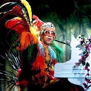 1977. Elton John amid colorful feathers on The Muppet Show.
