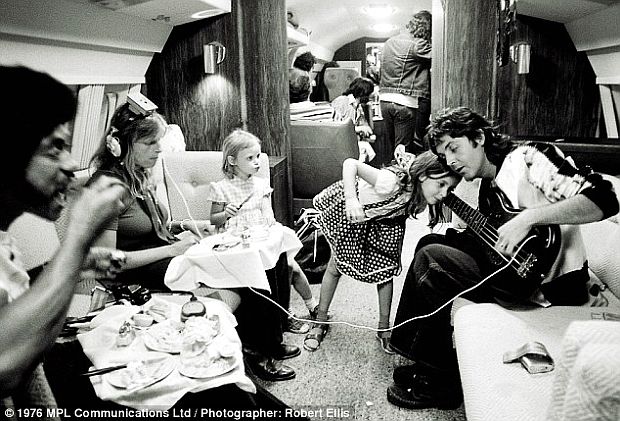 June 1976. The McCartneys & crew during dinner aboard their private jet over America during Wings tour. Mary is trying to hear Paul's guitar while Linda listens on headphones across the aisle, and Stella, to Linda’s left, looks on.