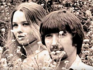 Michelle Phillips and Denny Doherty, amid the flowers.