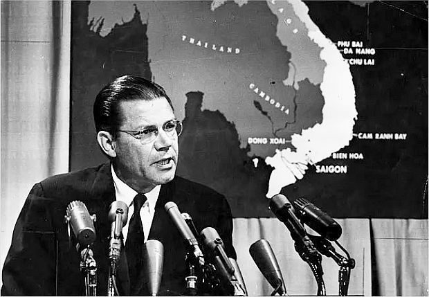 1965. U.S. Secretary of Defense, Robert McNamara, giving a briefing during the Vietnam War, with map of the region behind him.