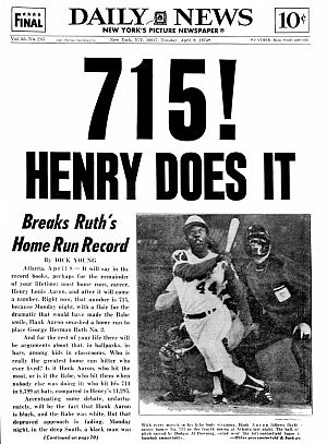 NY Daily News, April 9th, 1974: “715! Henry Does It!,” with photo of Aaron completing his swing, his eyes on the ball’s flight. Click for replica tin poster.