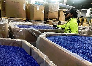 Plastics factory in New Jersey with worker walking amid large containers of blue-colored plastic nurdles. Laura Sullivan/NPR.