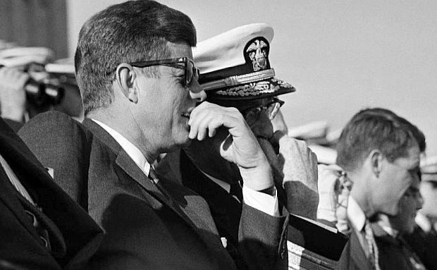 President John F. Kennedy at the 1962 Army-Navy game, seated next to some Navy brass, along with his brother, Robert F. Kennedy, seated further down the row. The president spent one half on the Navy side and one half on the Army side.  AP photo.