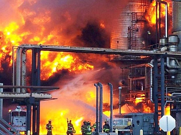 Photo of the raging inferno at the Chevron oil refinery in Richmond, California, August 2012. Note group of firefighters at bottom of photo for scale comparison. Photo from CSB’s subsequent 2014 report.