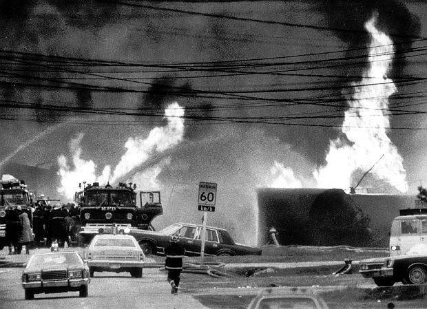 Looking down roadway at Mississauga, Ontario into the train wreck scene where derailed chemical tankers and other Canadian Pacific rail cars were blazing as firefighters did their best to quell multiple infernos
